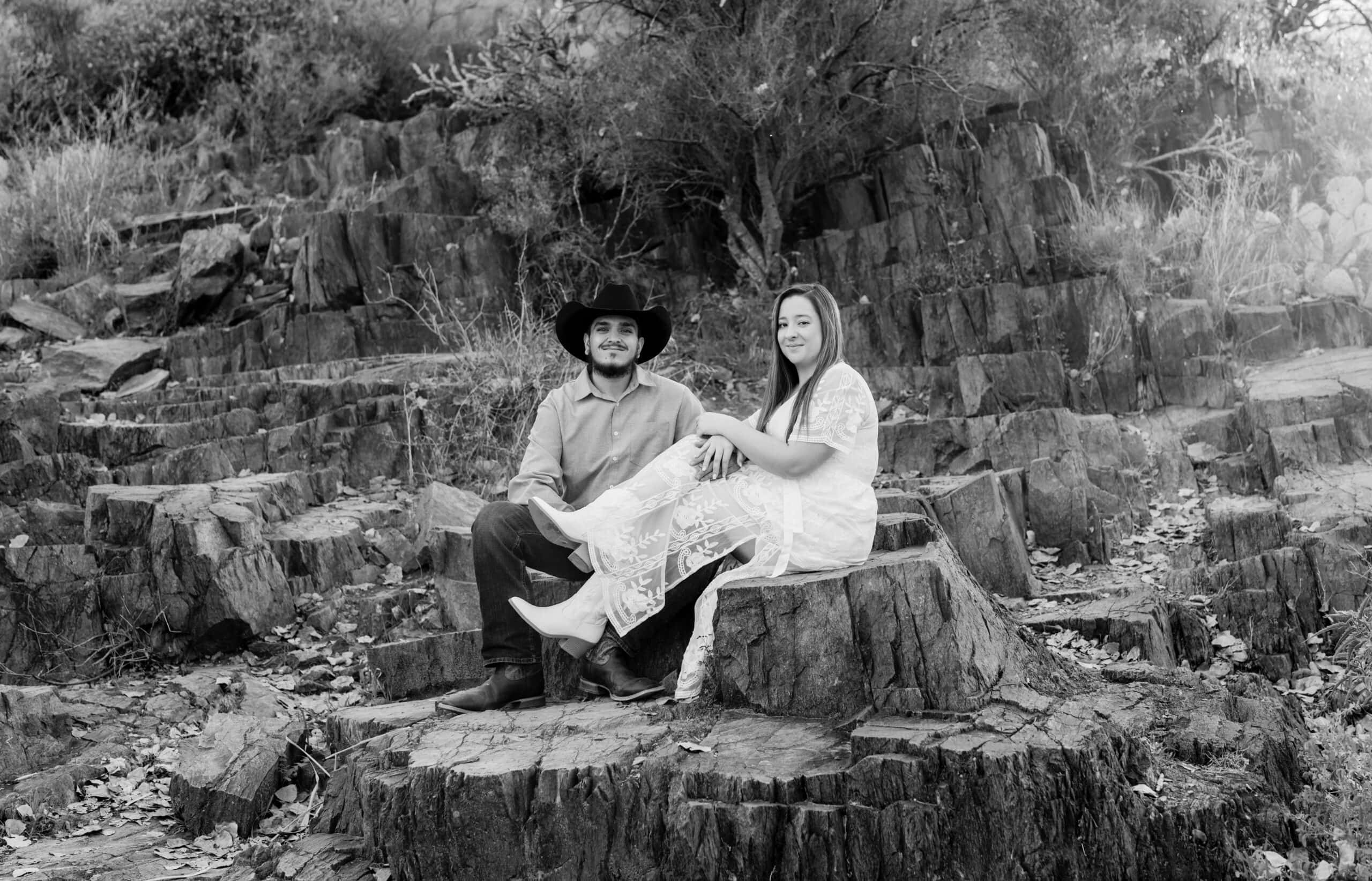 Bride and groom embracing in desert setting with rugged rocks and cacti background