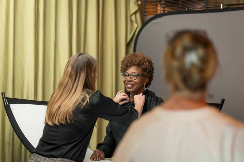 Event staff preparing speaker with lapel microphone ahead of corporate interview session