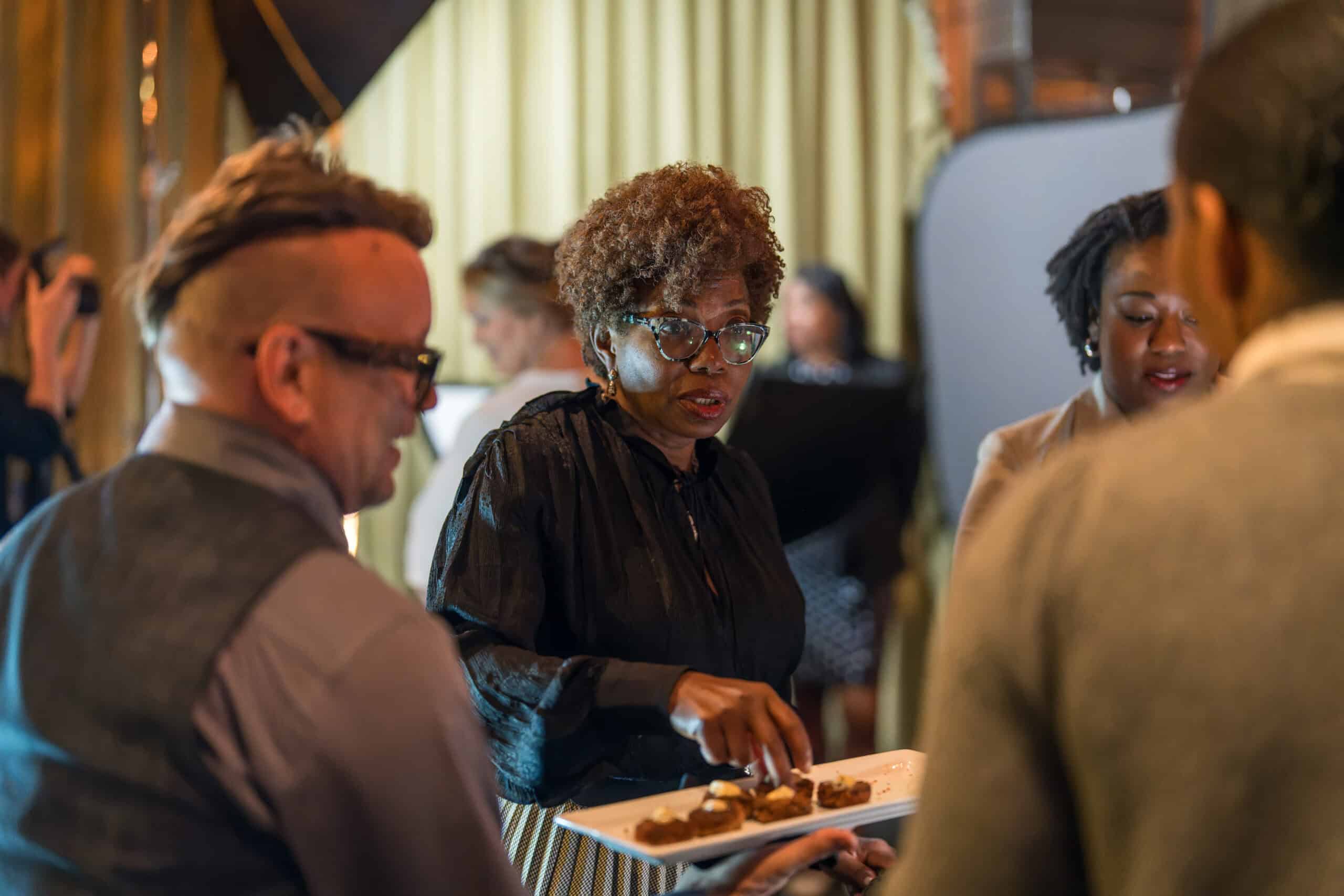 Woman offering plated appetizers at intimate Virginia Beach business mixer