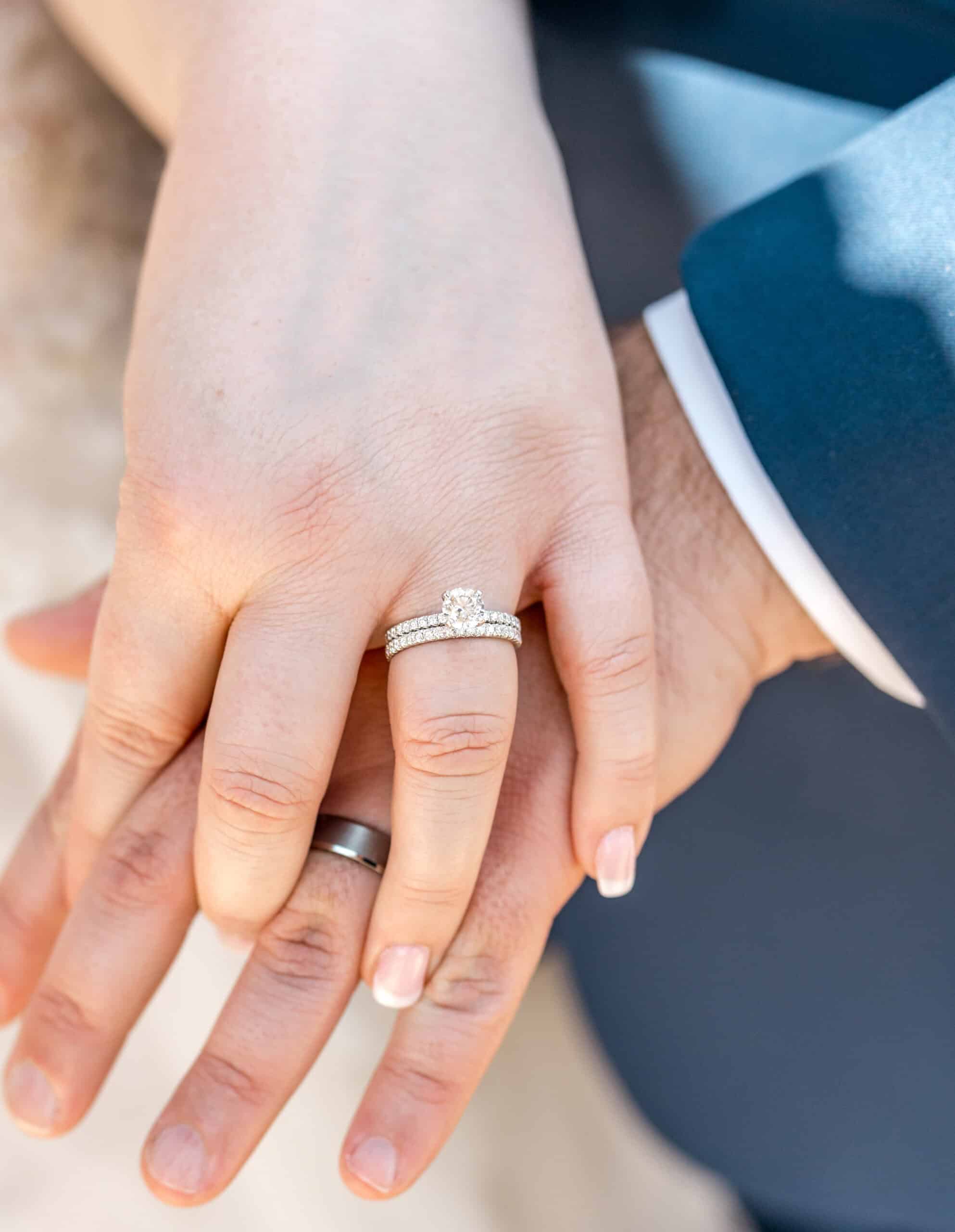 Close-up of newlywed couple holding hands showing wedding rings in Virginia Beach