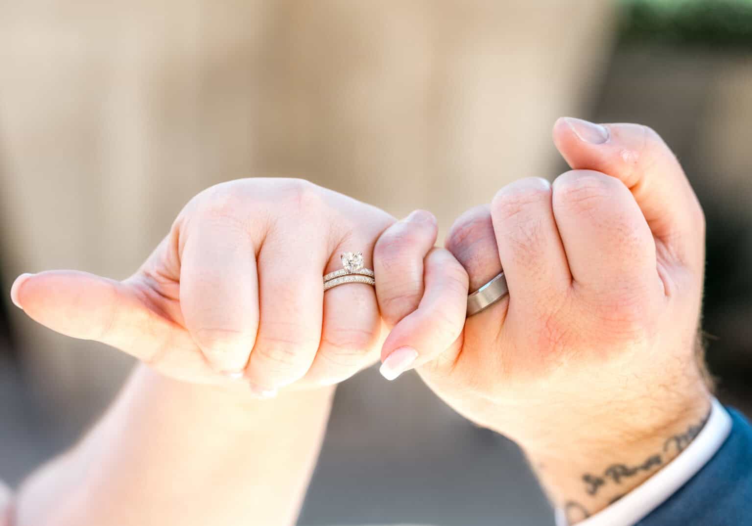 Bride and groom making pinky promise with wedding rings on display during Virginia Beach wedding