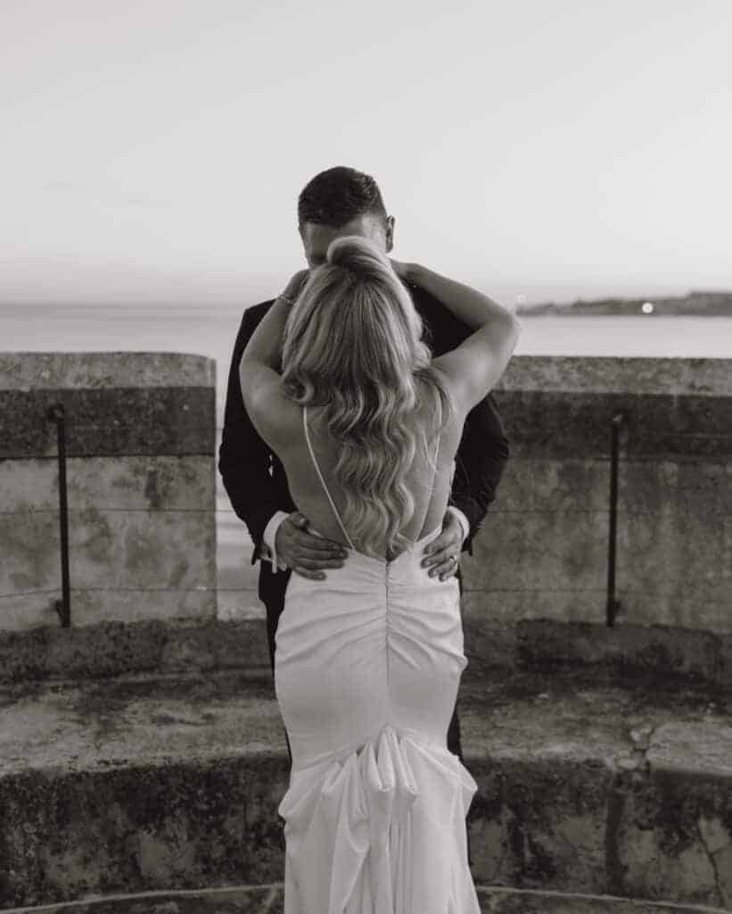 Bride and groom embracing on a beachfront terrace at sunset in Virginia Beach, captured by a Virginia Beach photographer
