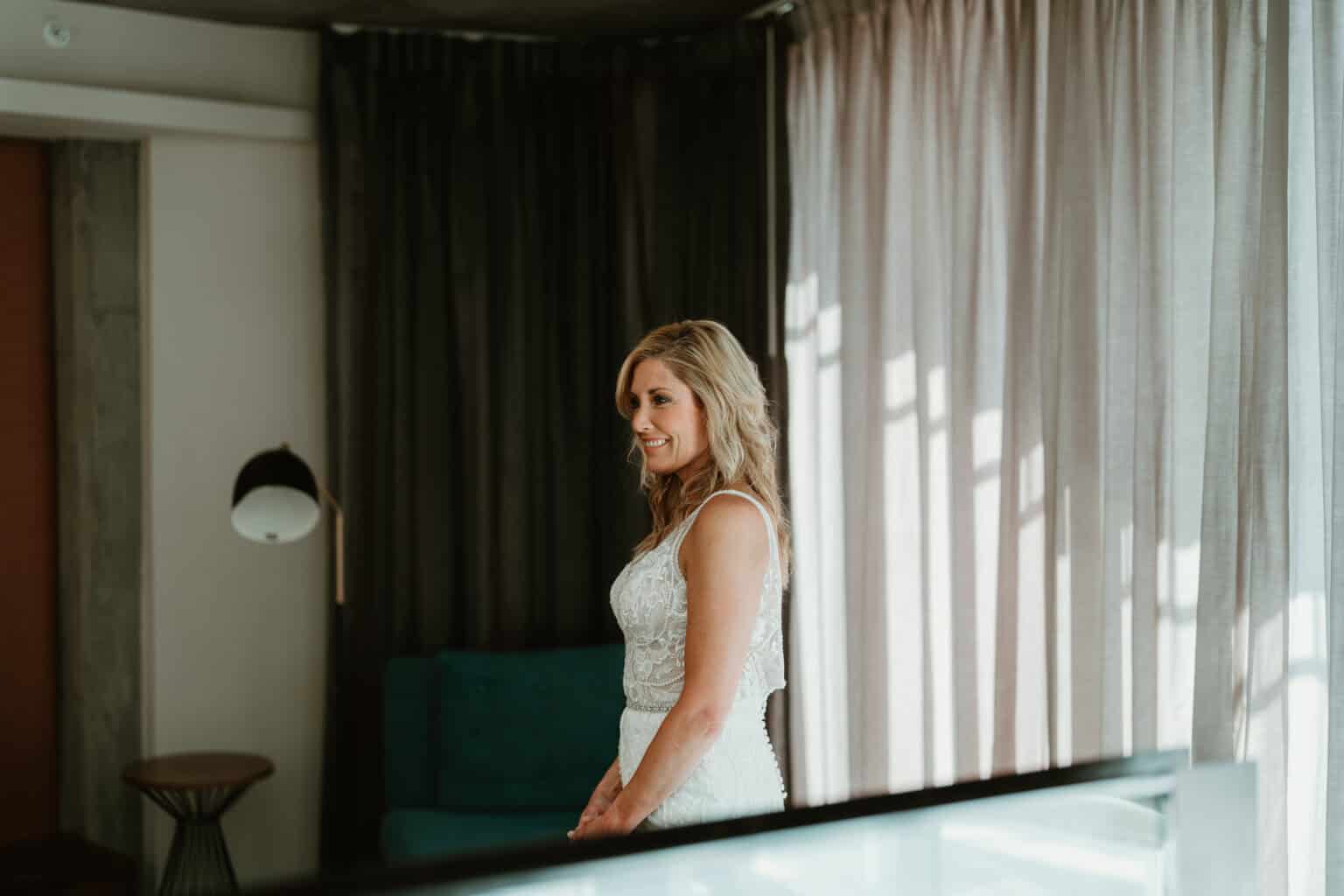 Smiling bride in natural window light during getting-ready moment in Virginia Beach