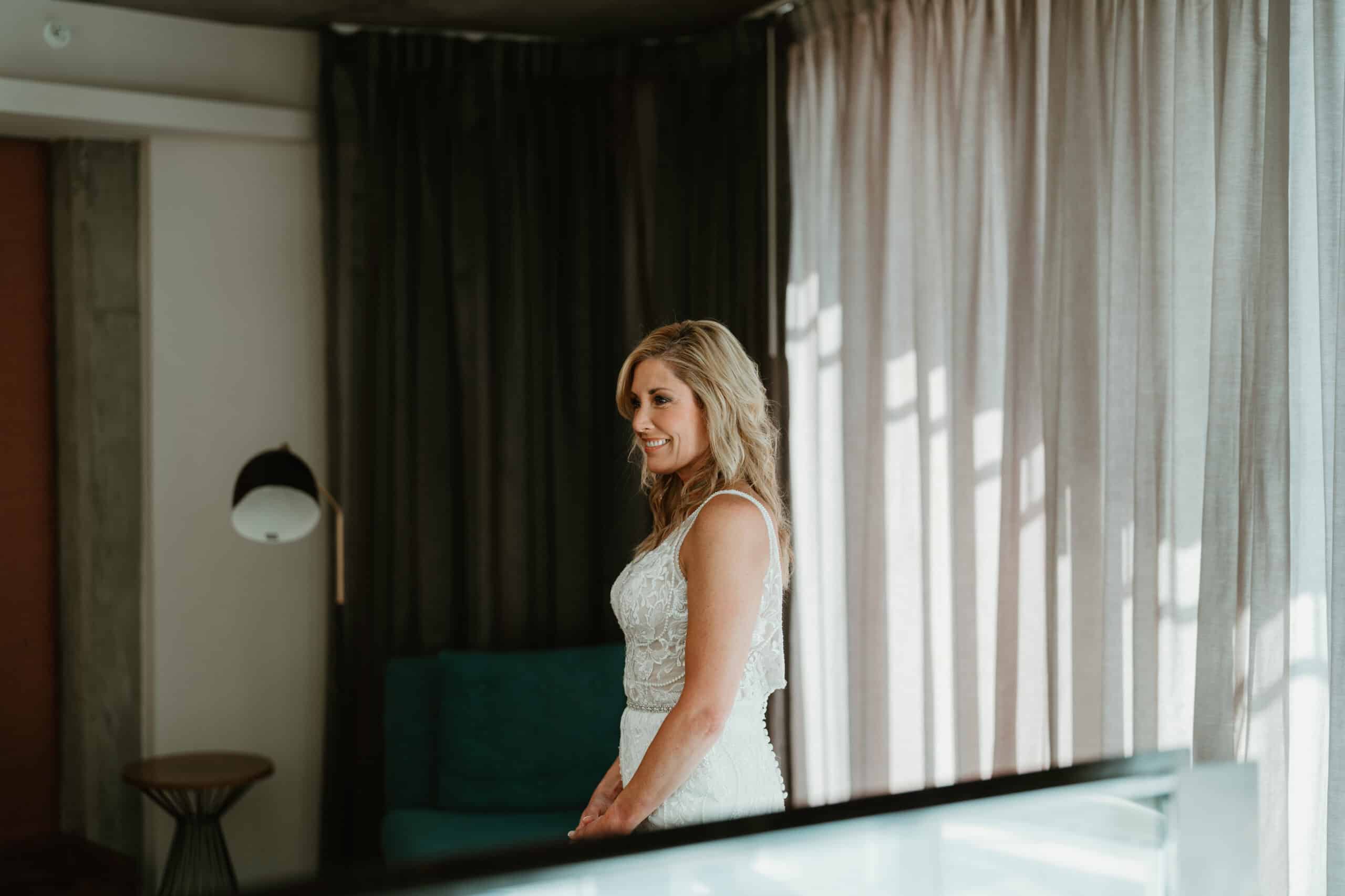 Smiling bride in natural window light during getting-ready moment in Virginia Beach