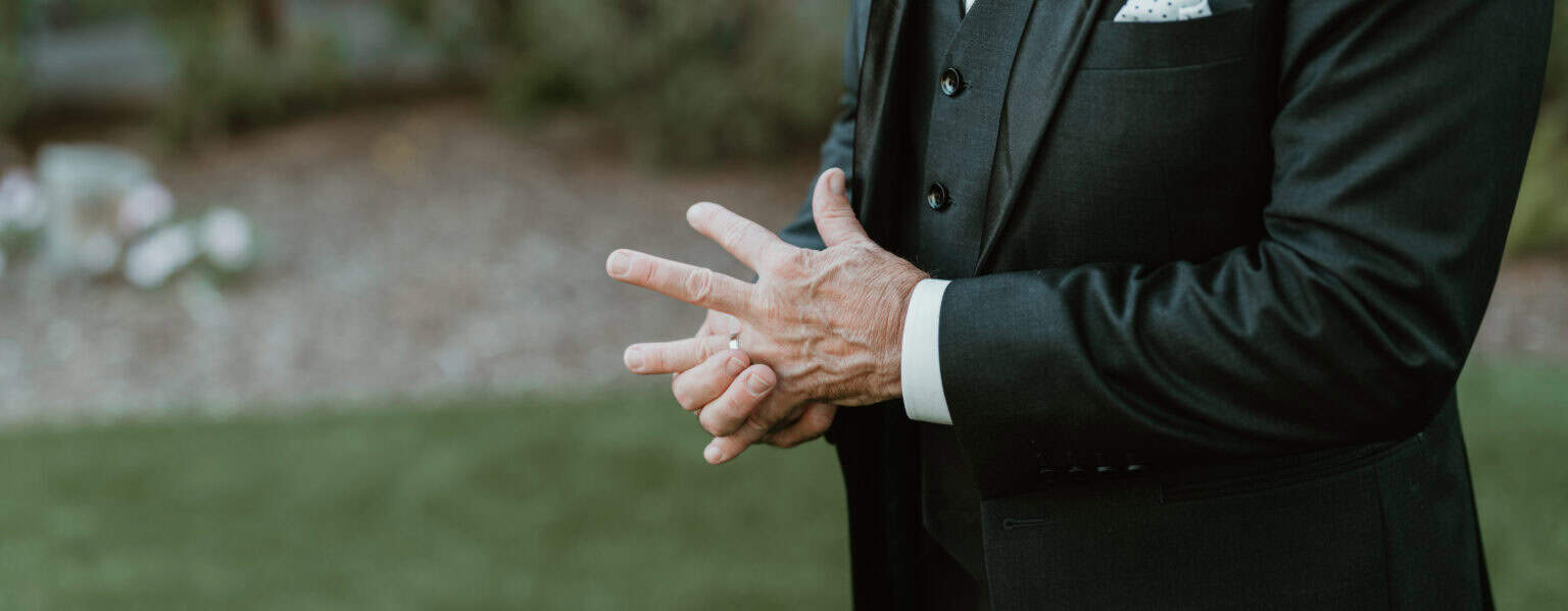 Groom in dark suit adjusting jacket cuff during Virginia Beach wedding portrait session