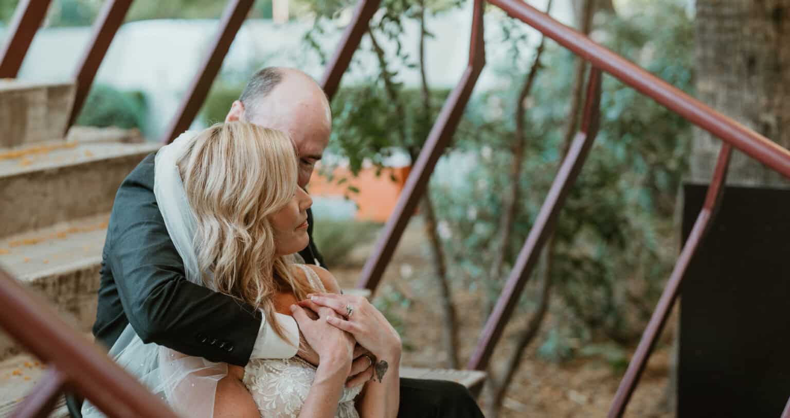 Virginia Beach bride and groom in intimate embrace on rustic outdoor staircase