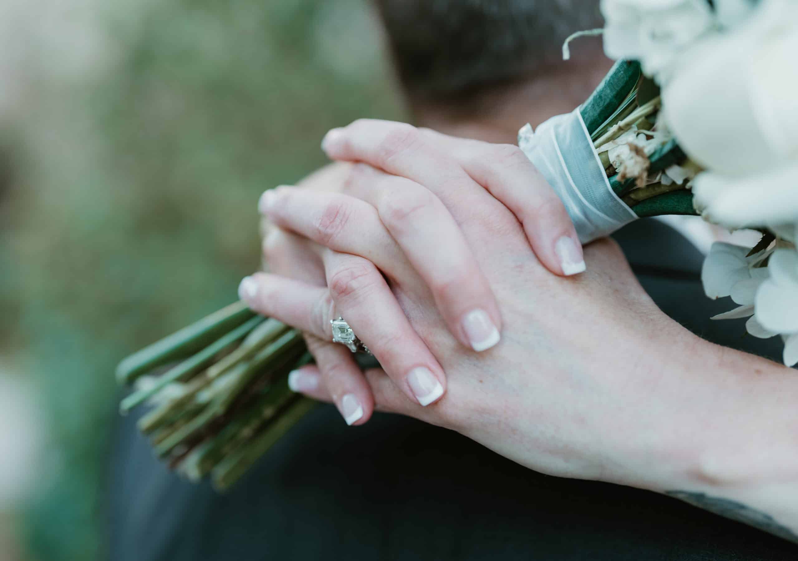 Close‑up of bridal bouquet with white roses and greenery against ceremony railing in Virginia Beach