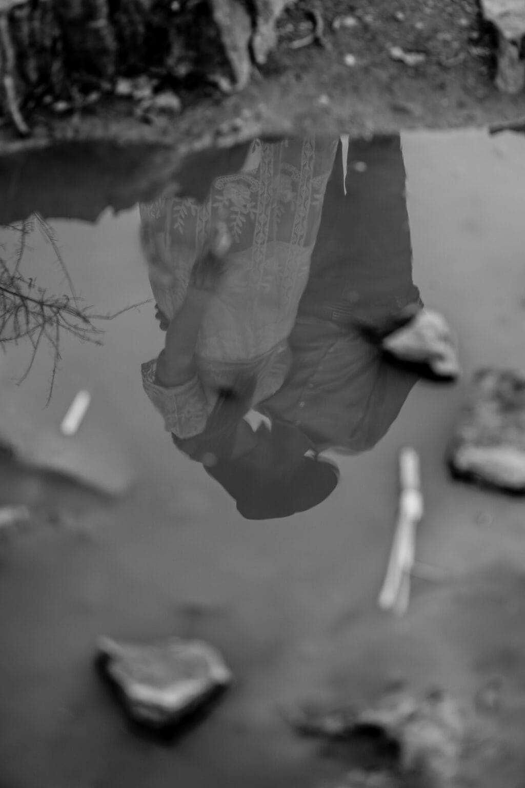 Creative reflection of engaged couple kissing in a puddle, captured in an artistic and romantic style.