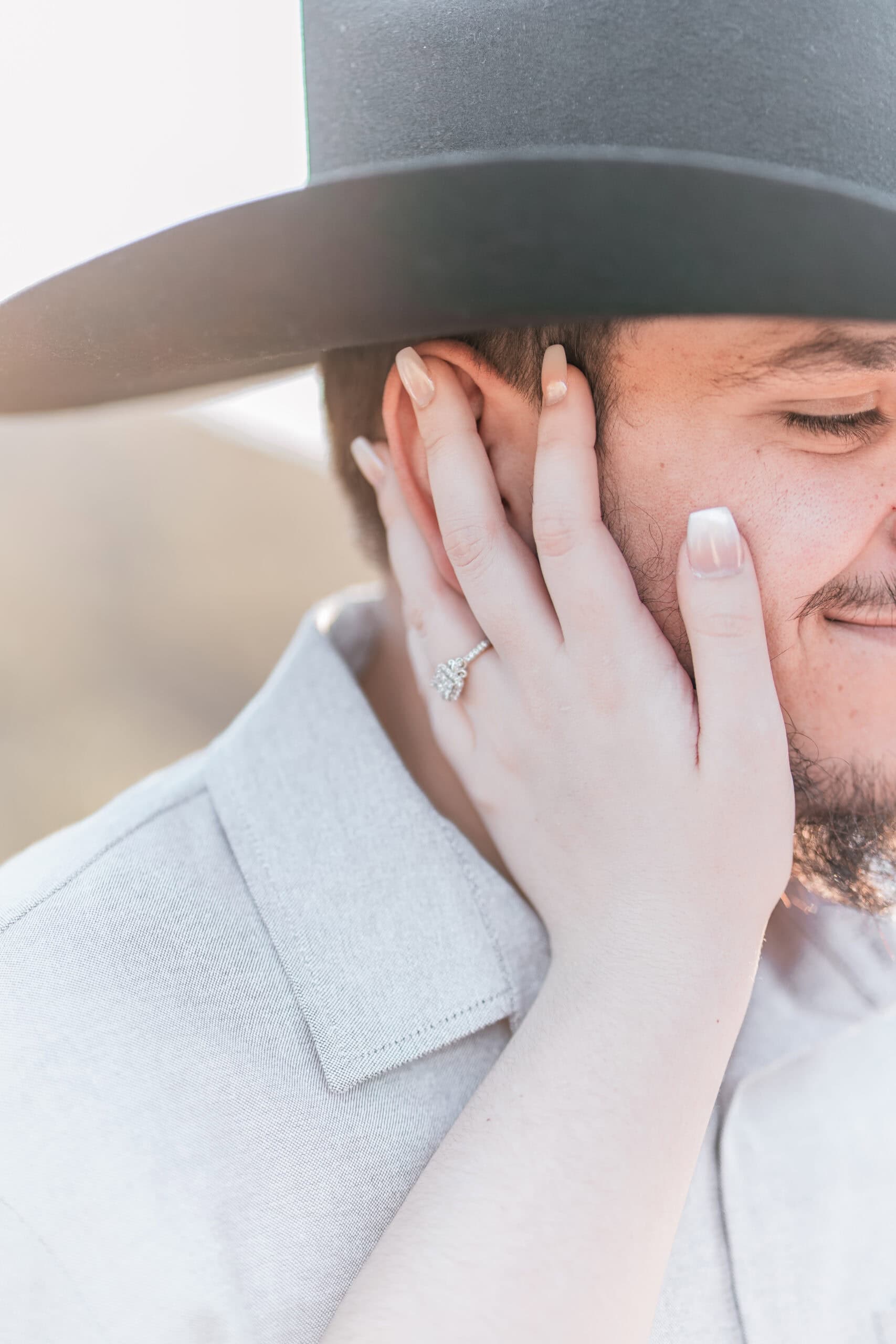 Bride’s hand with diamond ring resting on groom’s face during a romantic engagement moment in Virginia Beach.