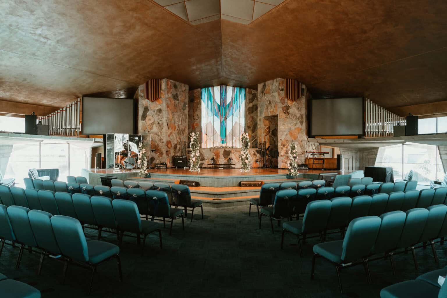 Wide view of a modern church sanctuary in Virginia Beach decorated for a wedding ceremony with blue seating and floral arrangements