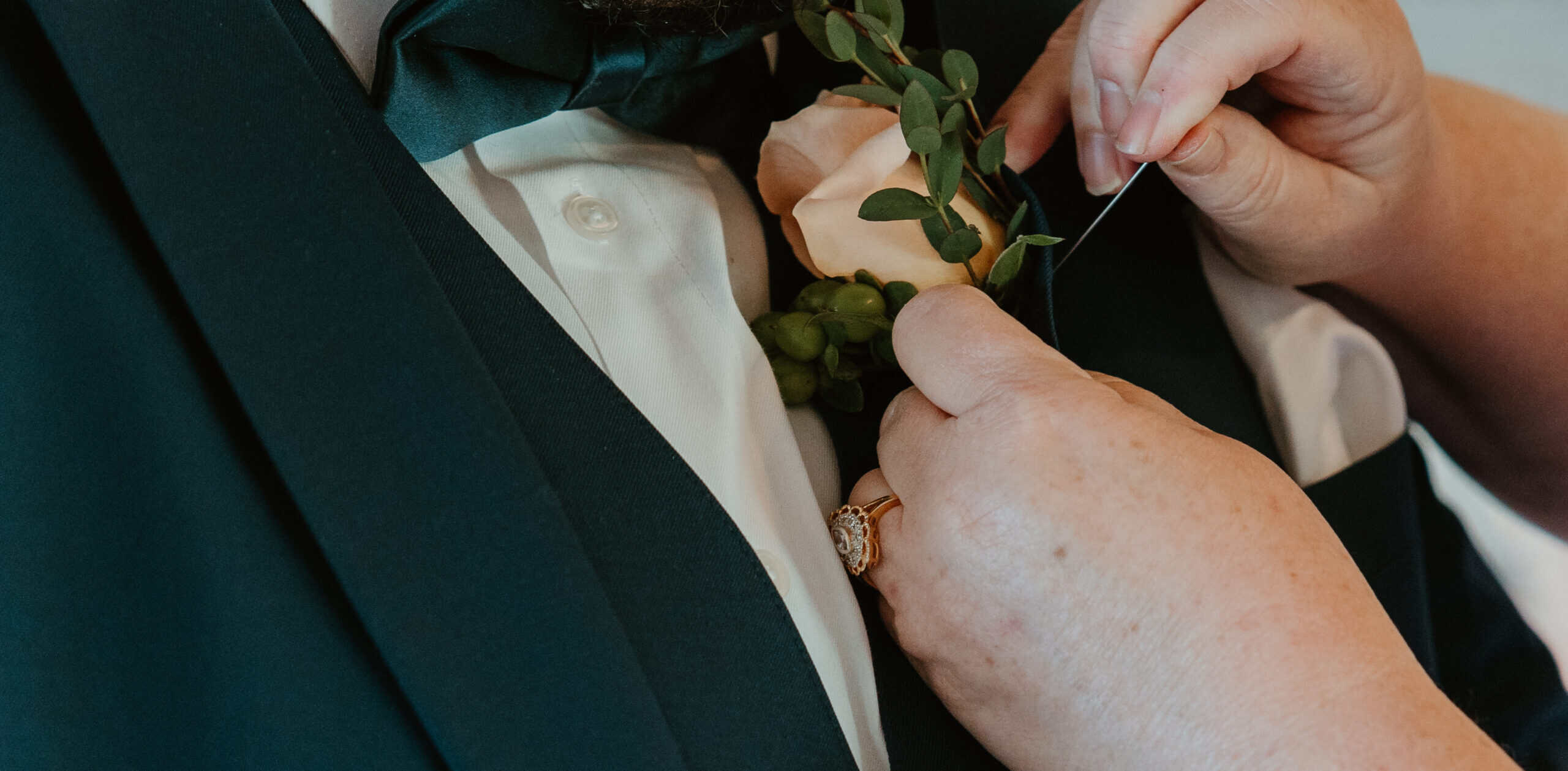 Close-up of a groom’s boutonniere being pinned by a loved one during wedding prep in Virginia Beach