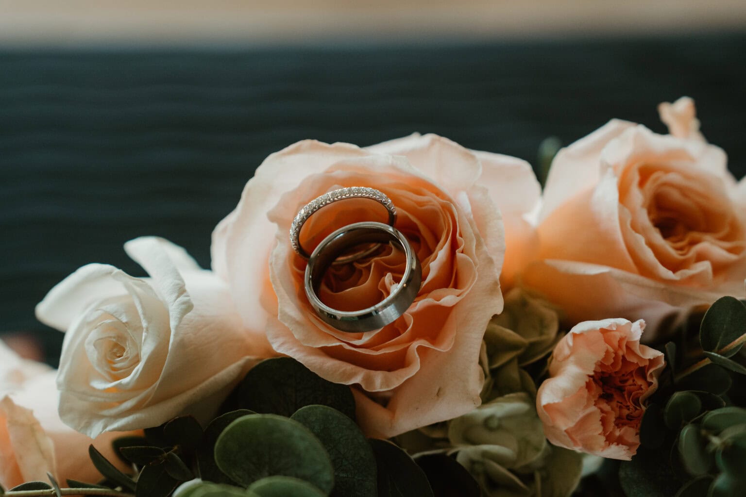 Bride and groom's wedding bands nestled in peach rose bridal bouquet – Virginia Beach wedding