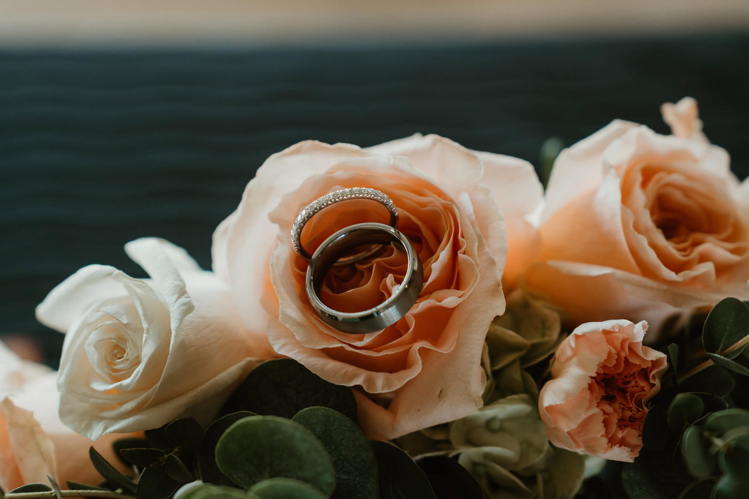 Bride and groom's wedding bands nestled in peach rose bridal bouquet – Virginia Beach wedding