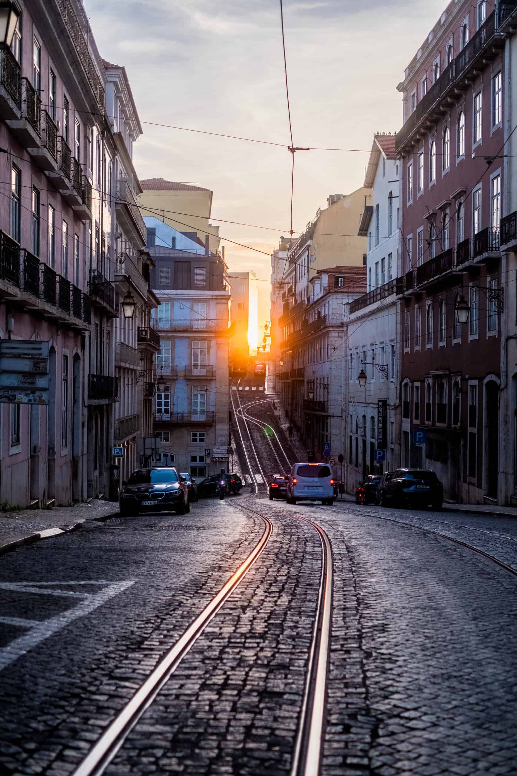 Golden sunset glowing down a tram-lined cobblestone street in Lisbon, Portugal