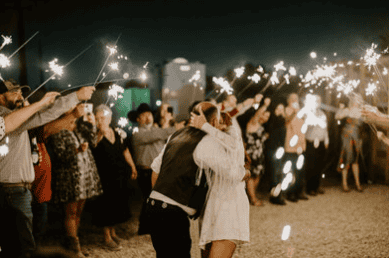 Newlyweds share a kiss during their nighttime sparkler exit at a Virginia Beach wedding celebration