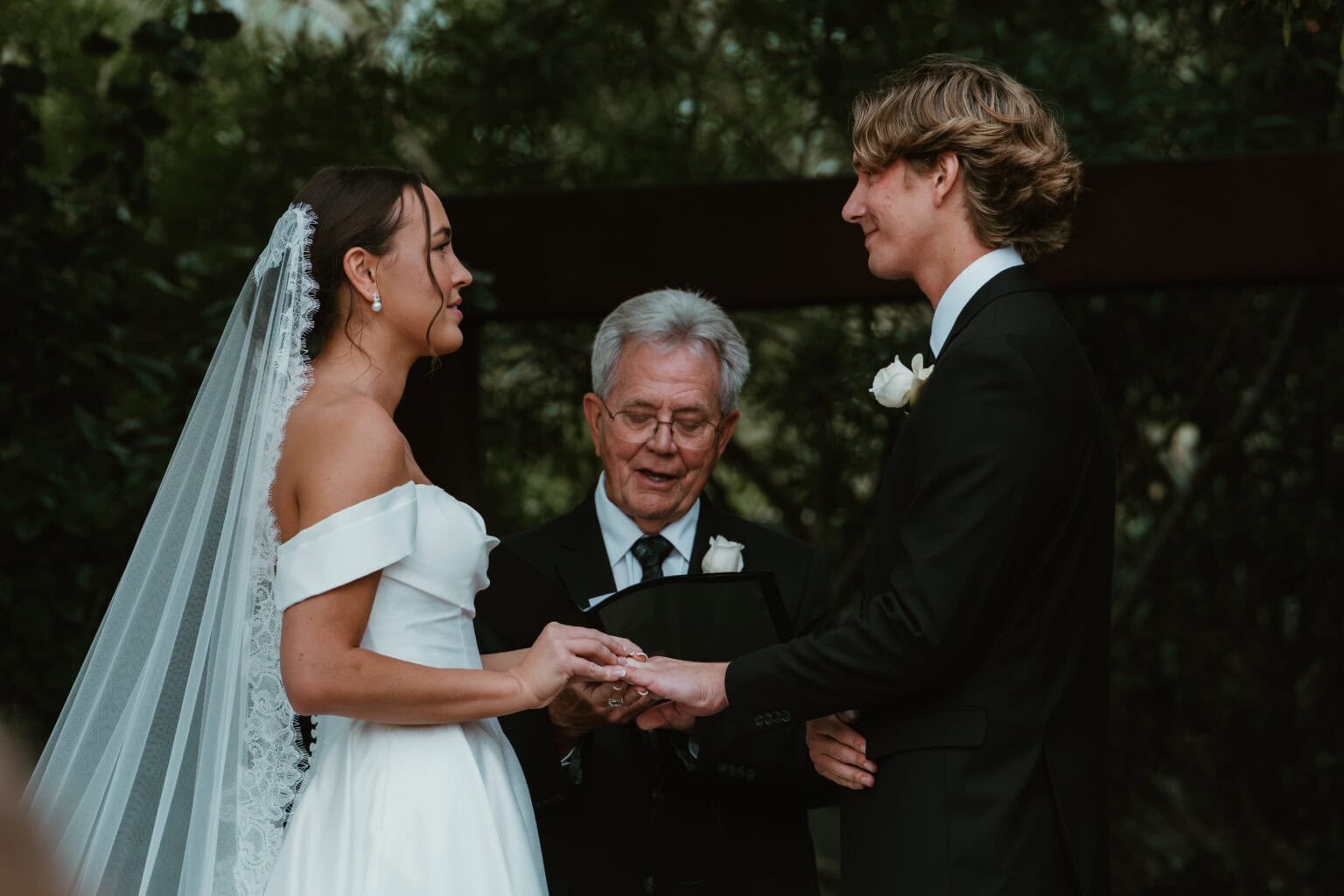 Bride and groom exchanging rings as the officiant reads during their outdoor wedding ceremony, by Captured in VA.
