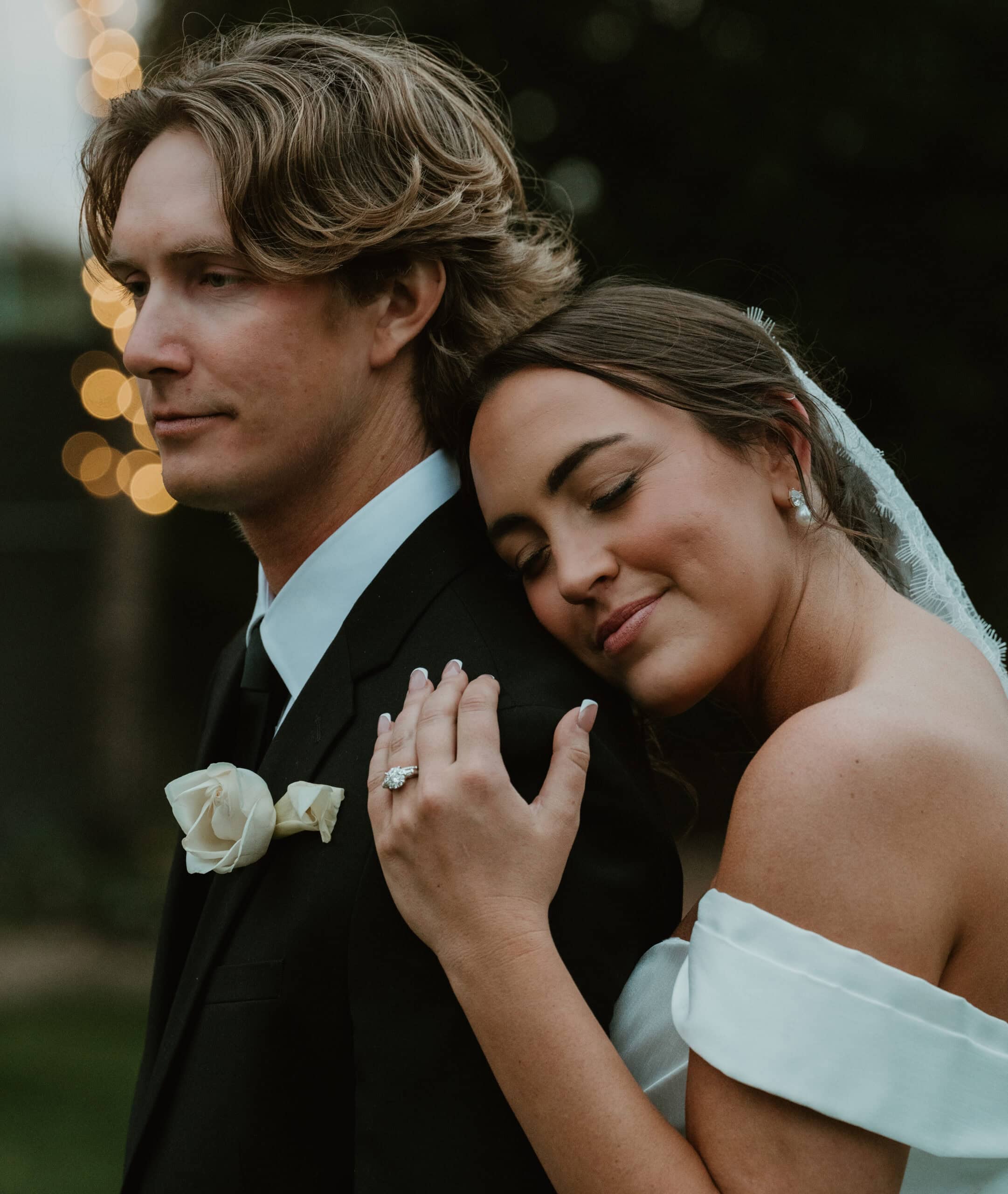 Bride resting her head on the groom's shoulder with her hand on his chest at golden hour, her ring visible, an intimate wedding portrait by Captured in VA.