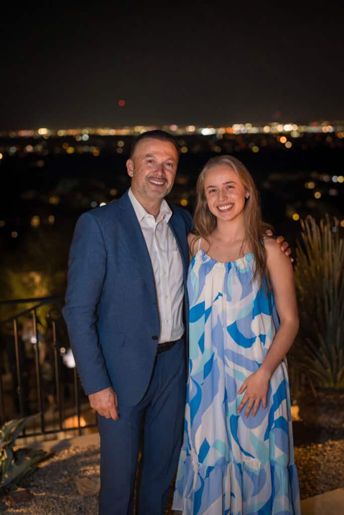 Smiling father and daughter at an evening birthday party with city lights behind them, event photography by Captured in VA.
