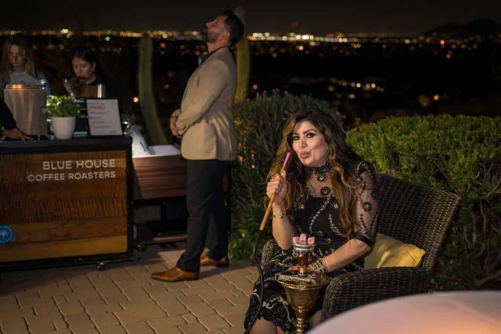 Guest in an embellished black dress enjoying hookah beside a coffee bar at an outdoor evening birthday party, event photography by Captured in VA.