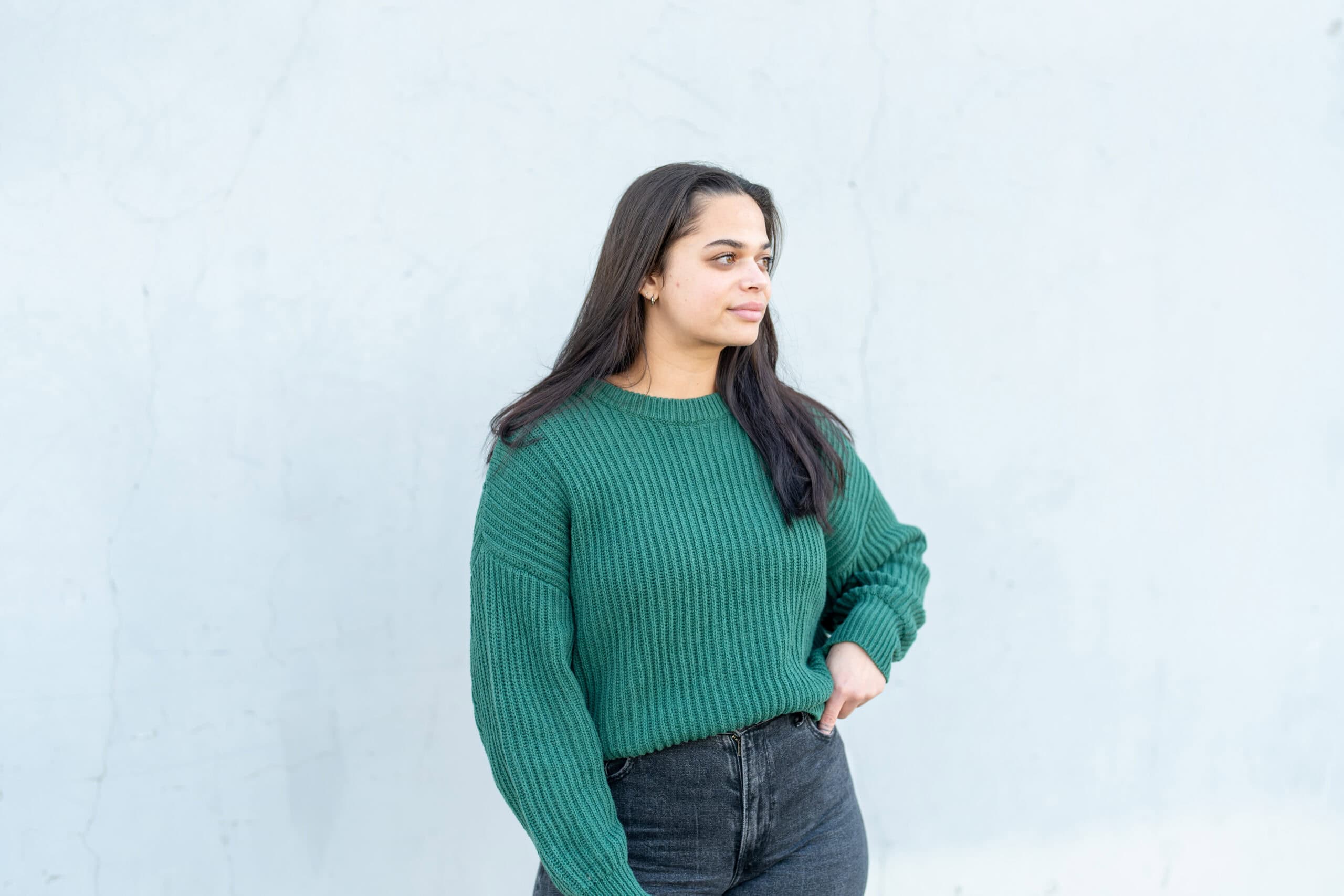 Individual portrait of a young woman in a green knit sweater looking off to the side against a soft white wall, by Captured in VA.